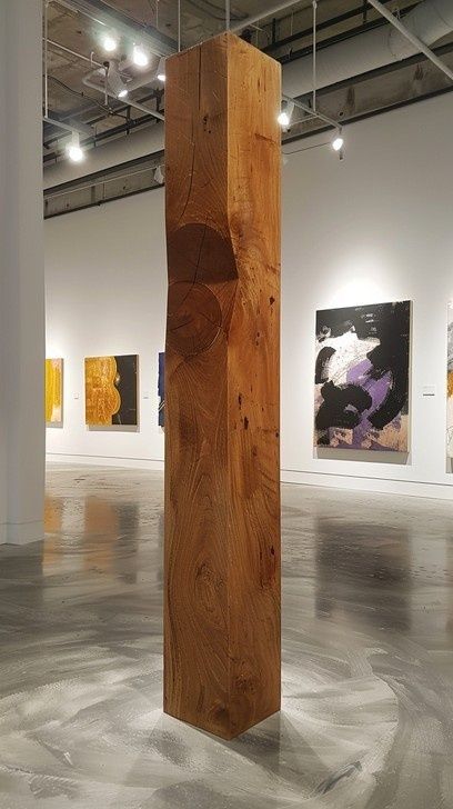 Sculpture en bois monumentale dans une galerie d’art silencieuse